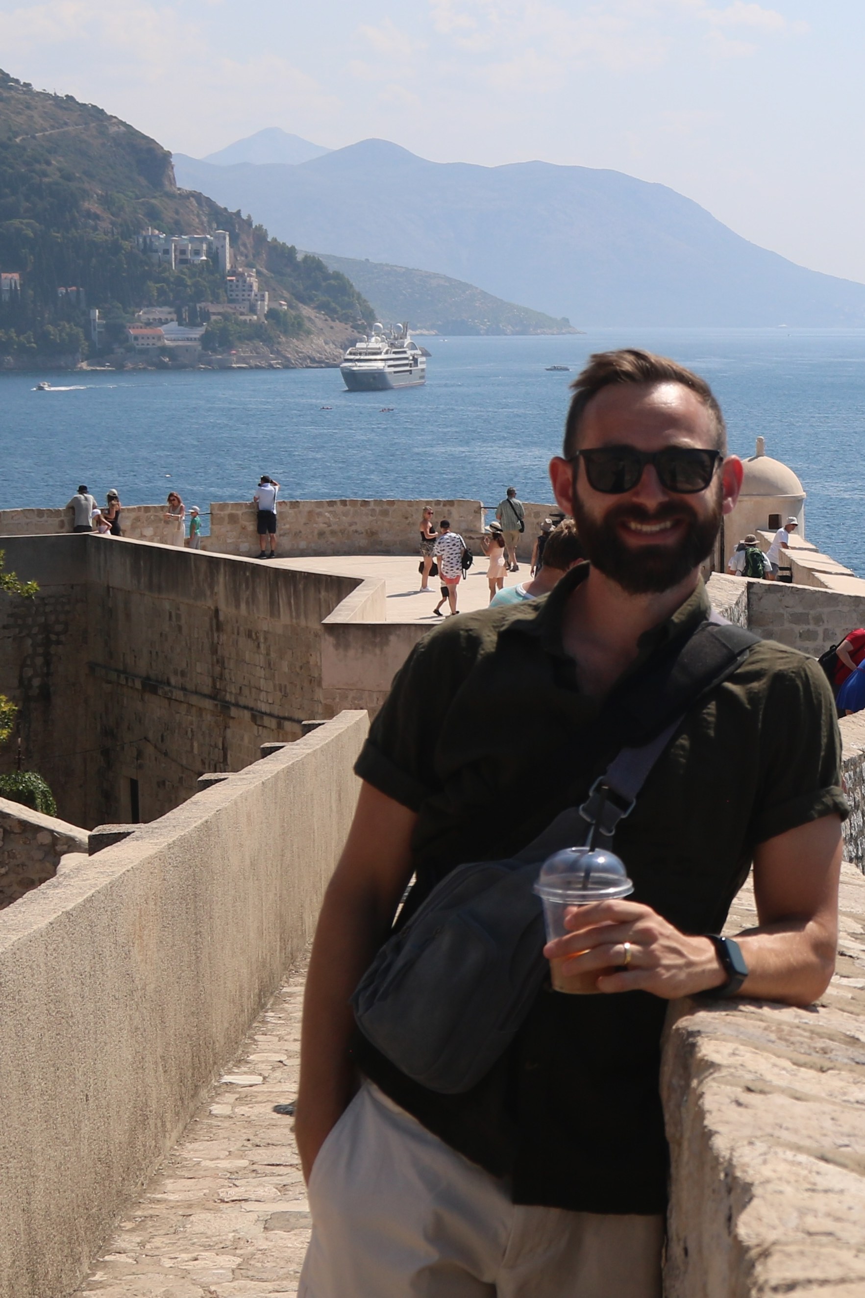 Benjamin Glasner standing on the walls of the old city of Dubrovnik with the harbor and Adriatic coast in the background.